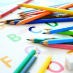 alphabetical letters and colored pencils with parents teaching kids phonics