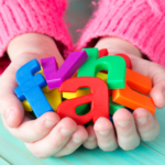 a child holding a collection of colorful plastic ABC letters in their hands