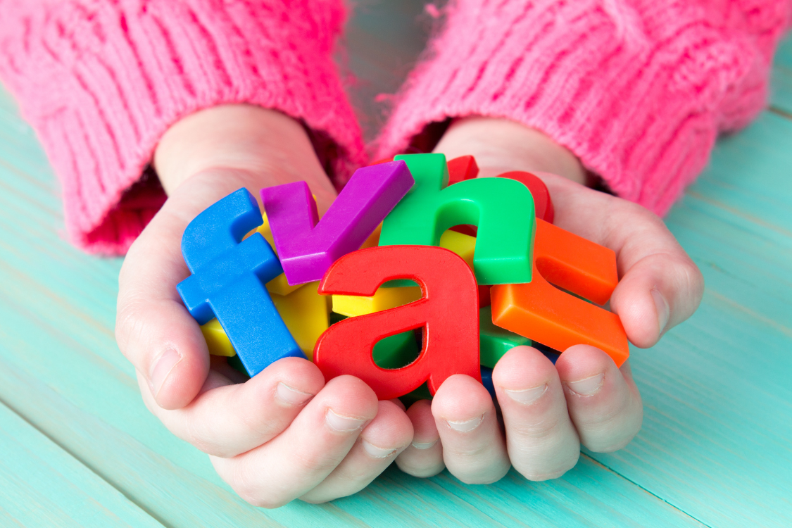 a child holding a collection of colorful plastic ABC letters in their hands