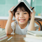 a bright smiling young girl is reading books