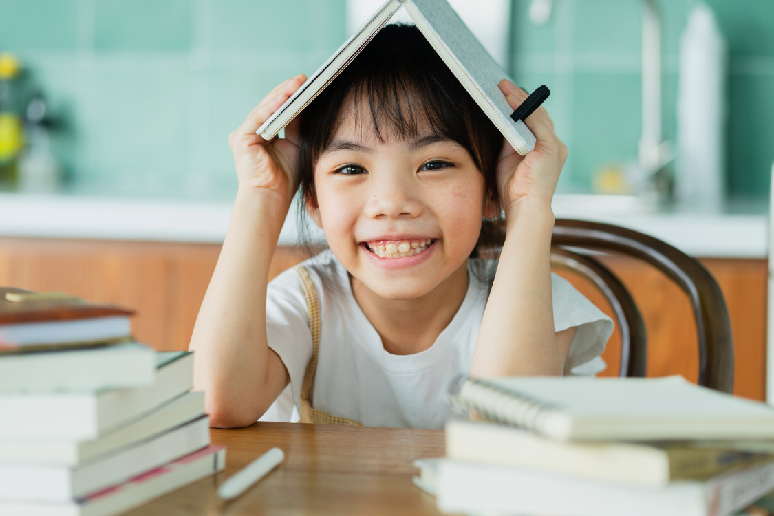 a bright smiling young girl is reading books